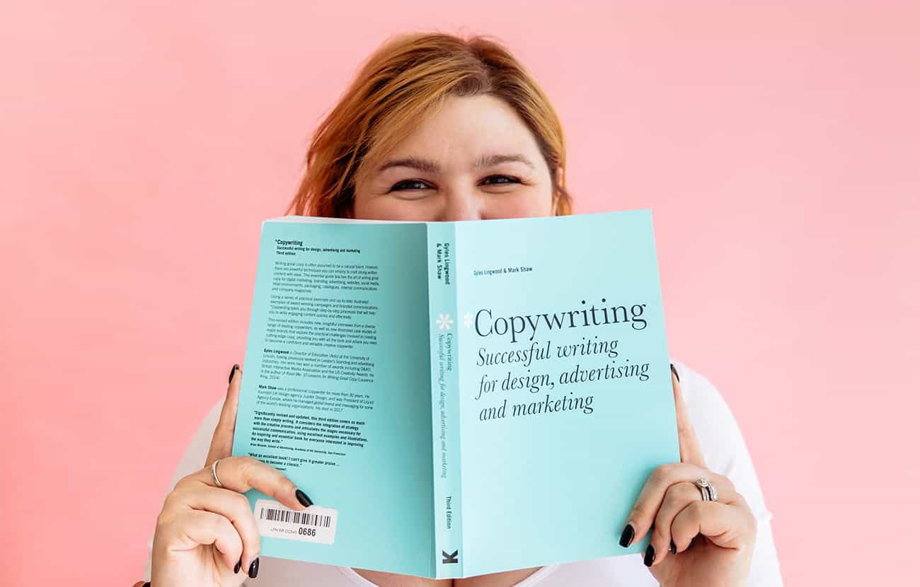 Matisse Nelis looking over the top of the book 'Copywriting - Successful writing for design, advertising and marketing'